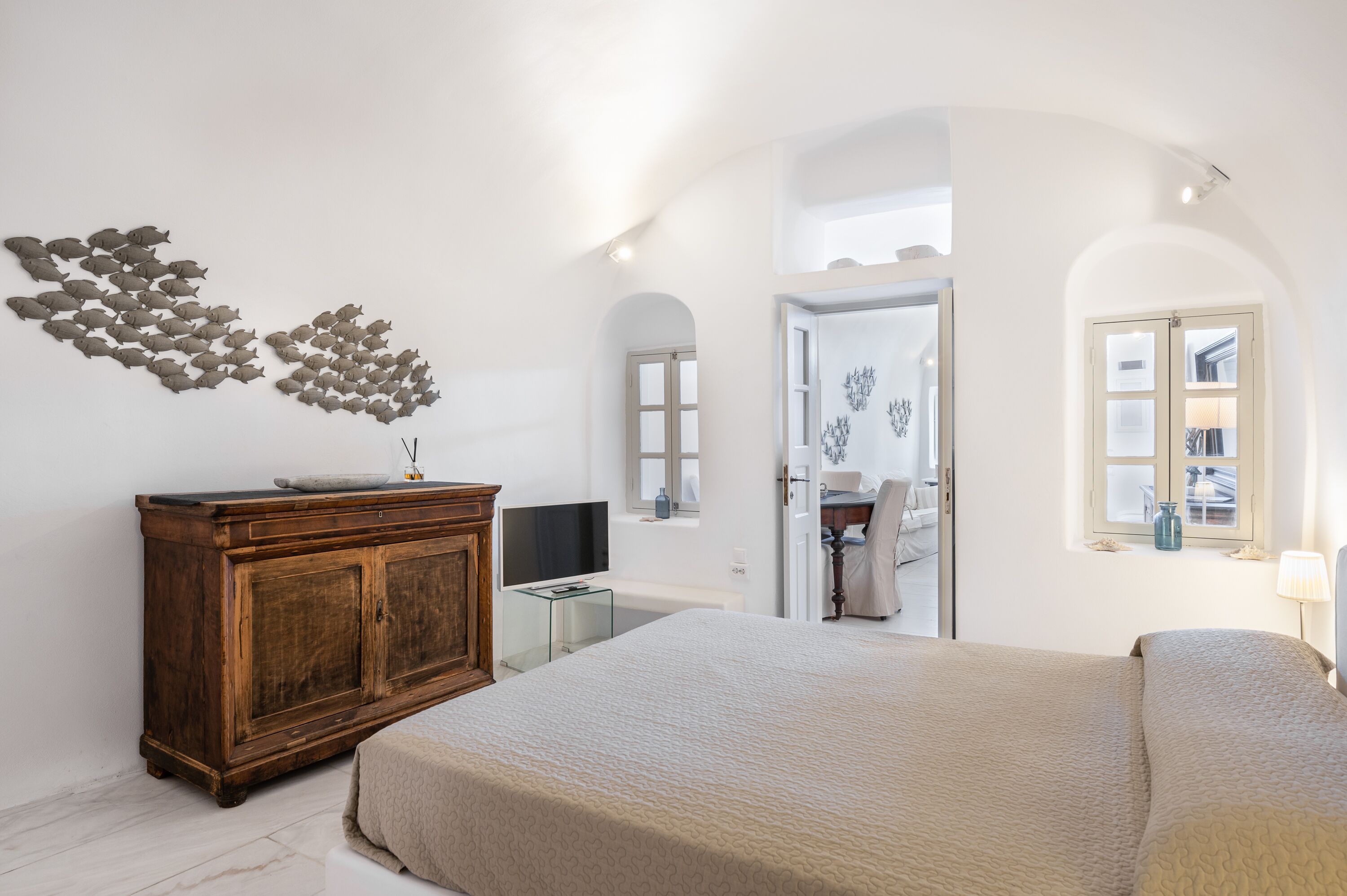 A bedroom with a large bed, a wooden dresser, a flat-screen TV, and a wall art piece.
