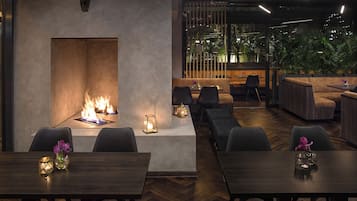 A modern interior with a fireplace, seating areas, and a view through a glass wall.