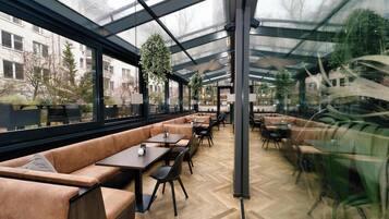 A modern indoor space with glass walls, leather seating, and tables.