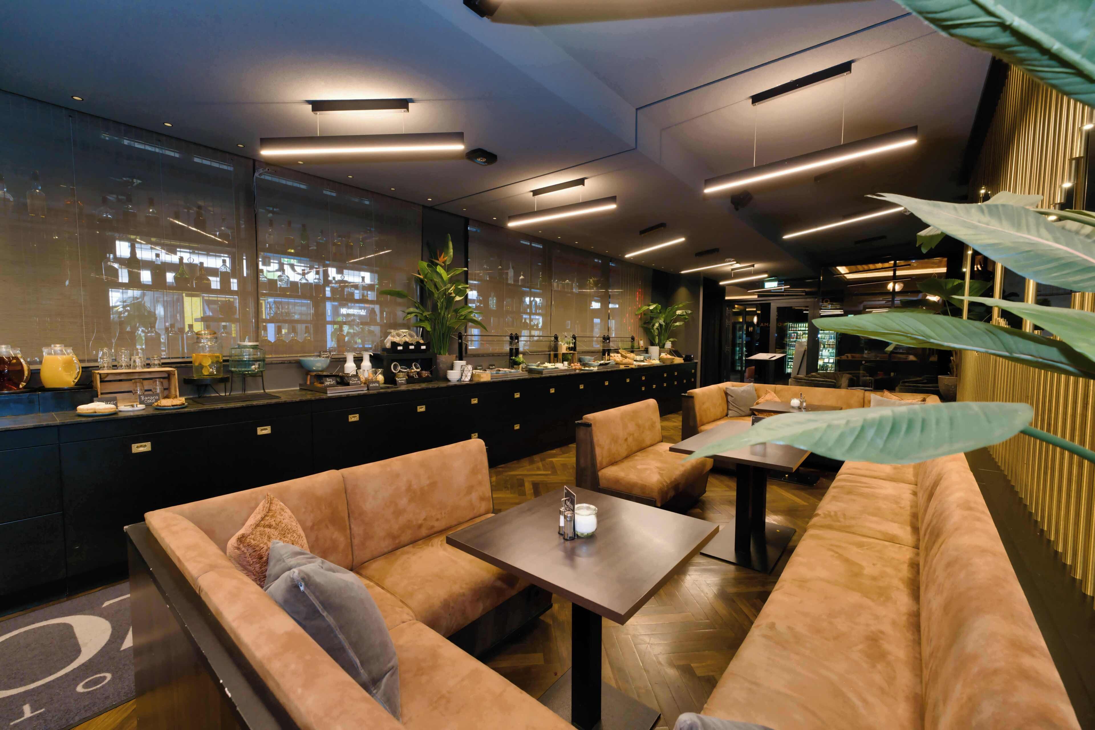 Un área de bar moderna con asientos, una barra y grandes ventanales.