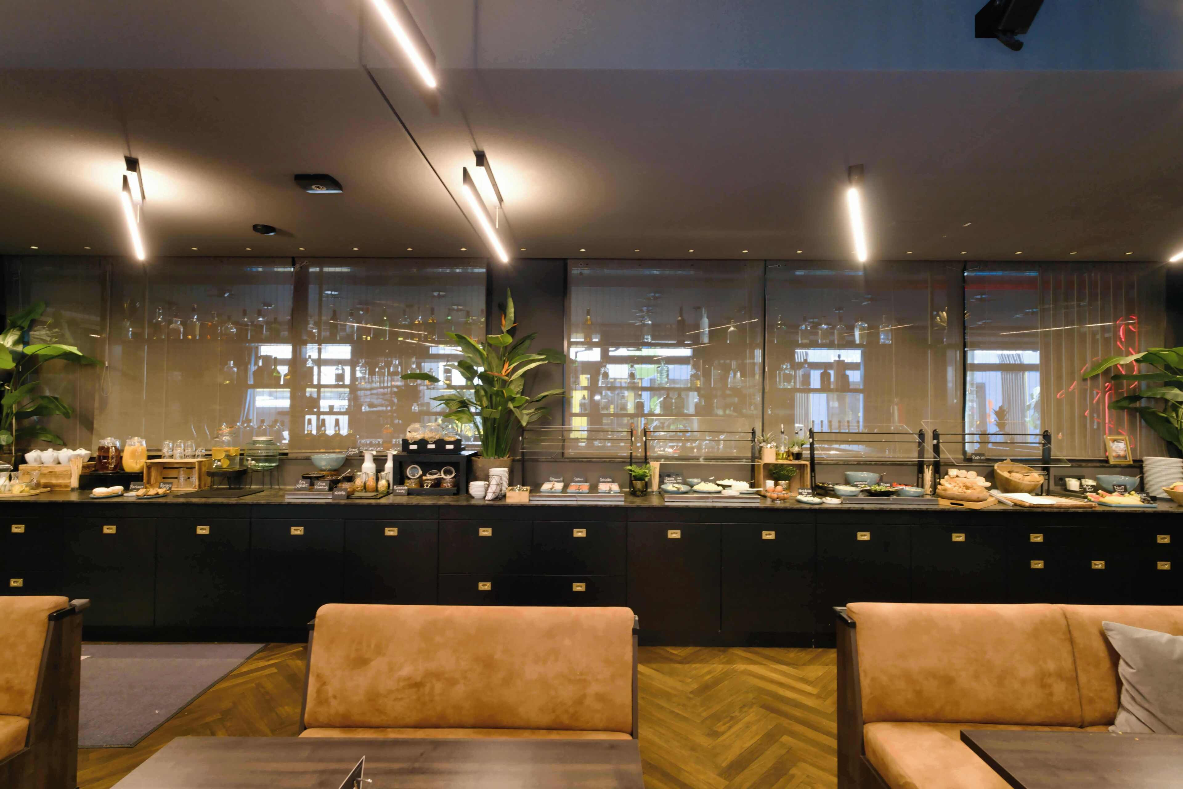 A modern hotel lobby with a reception desk, seating area, and large windows.