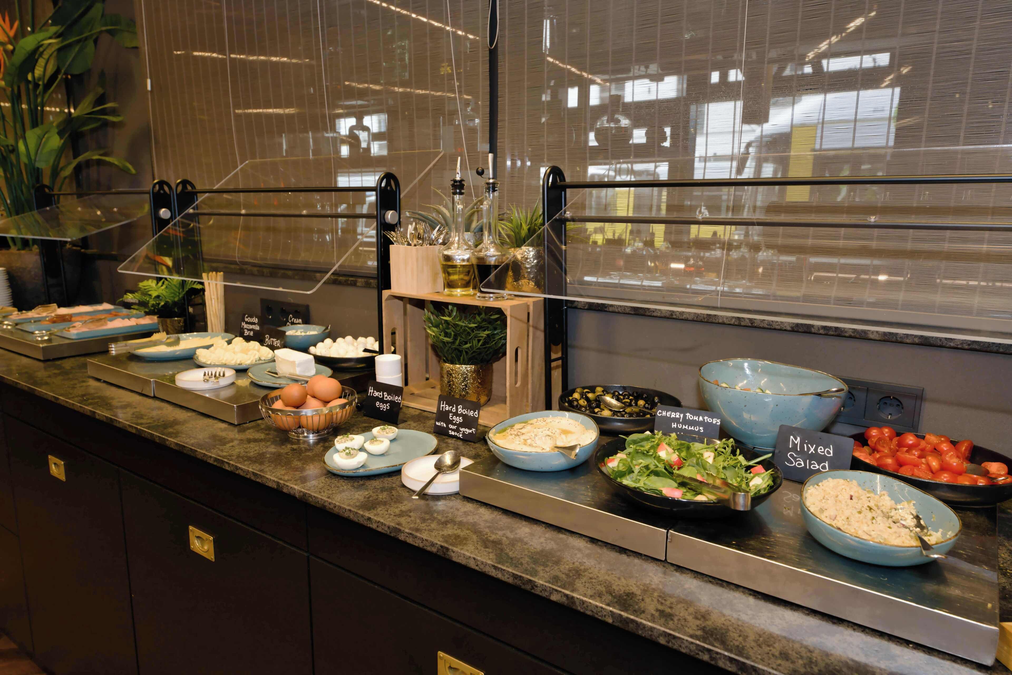 A buffet with various food options including hard-boiled eggs, mixed salad, and cherry tomatoes.