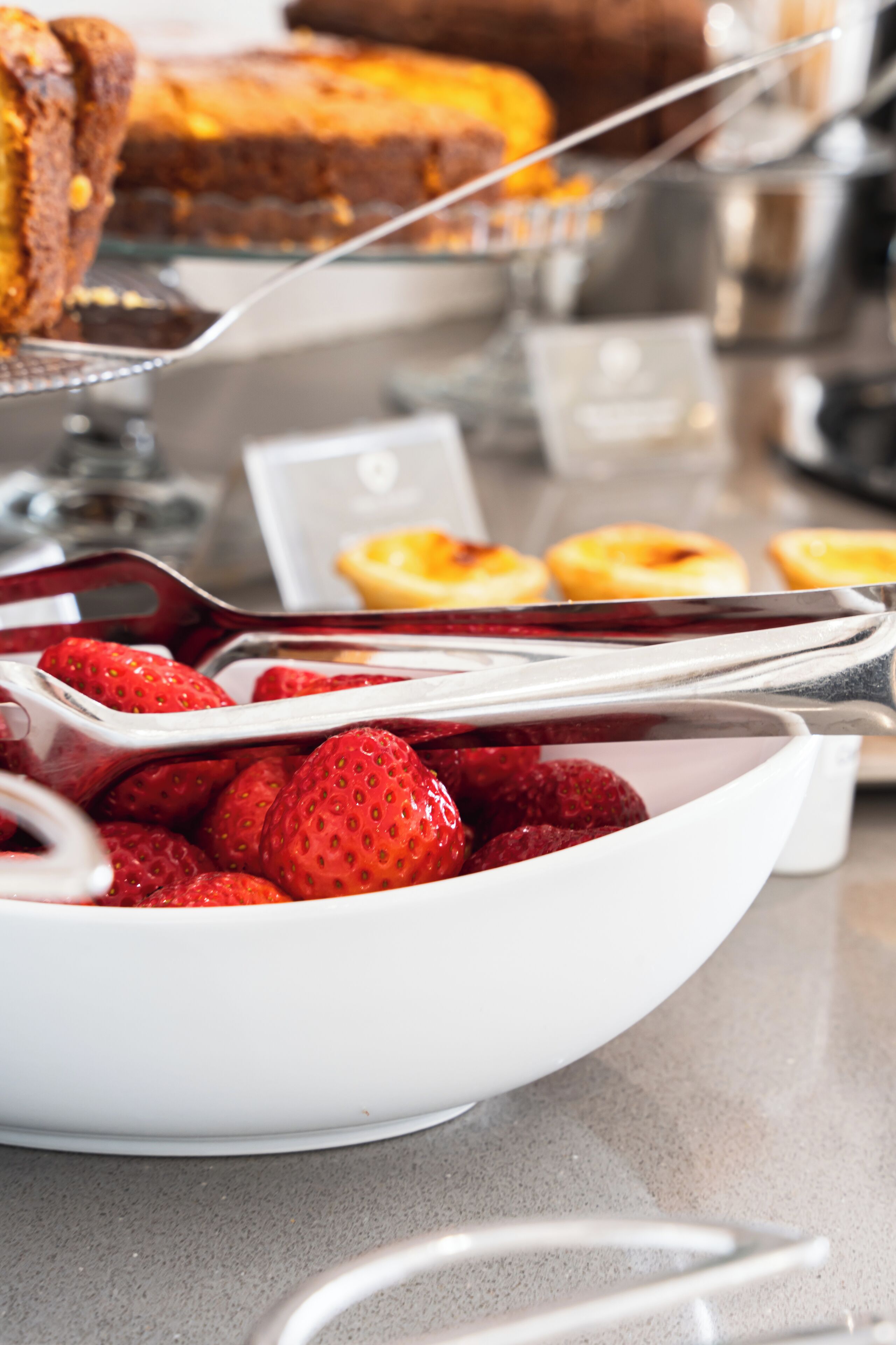 Un buffet proposant une variété de plats, notamment des fraises, des pâtisseries et un gâteau.