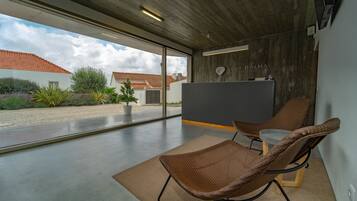 Ein modernes Interieur mit einer Rezeption, zwei Korbstühlen und einem großen Fenster mit Blick nach draußen.