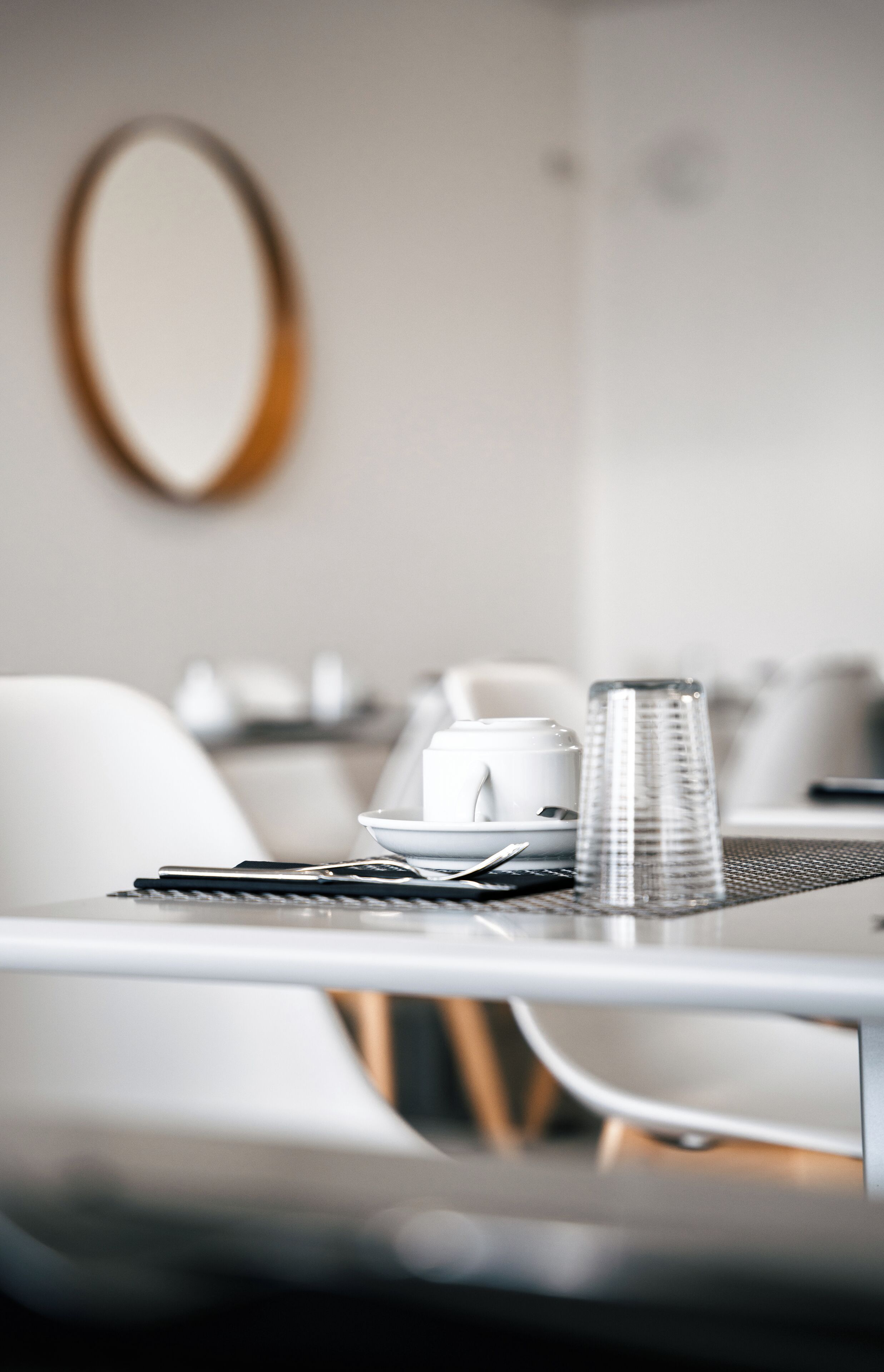 A dining table with a white plate, a cup, and a smartphone.