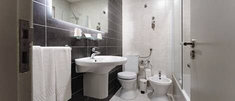 A modern bathroom with a sink, toilet, bidet, and a glass shower enclosure.