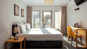 Habitación de hotel con cama, escritorio, silla, lámpara, televisión y aire acondicionado.