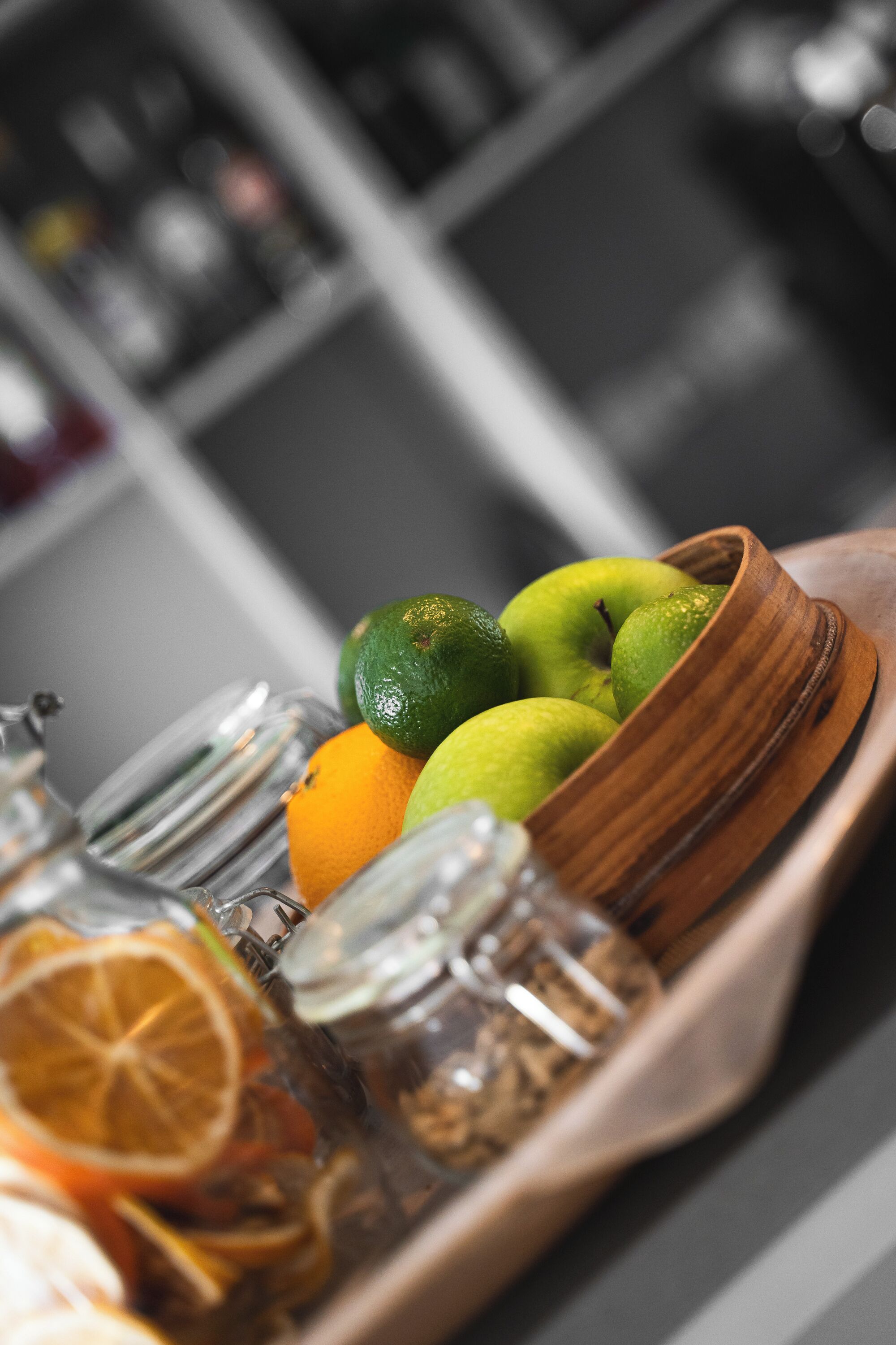 Una bandeja de madera con lima, naranja y un tarro de vidrio.