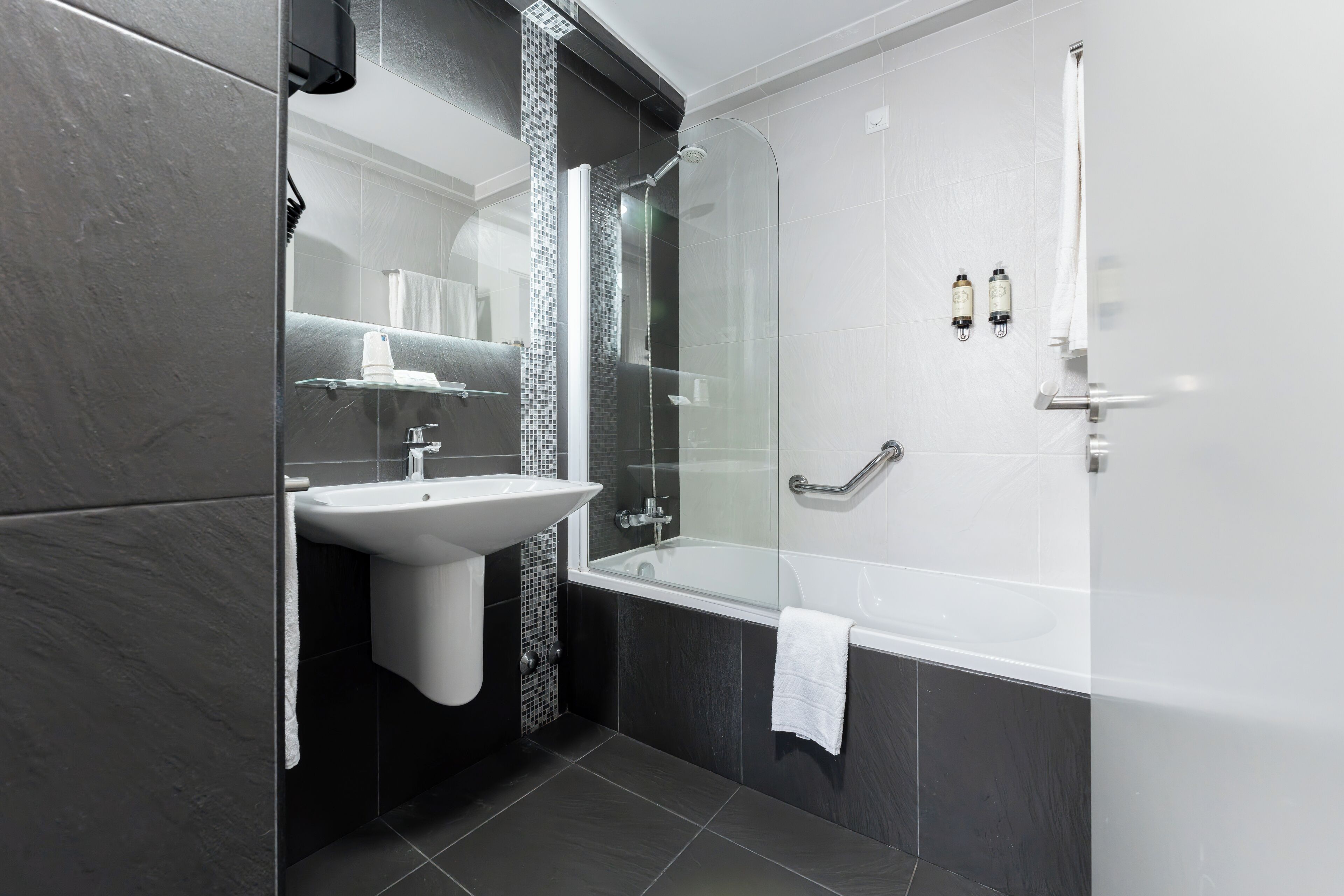 Un bagno moderno con doccia vetrata, lavandino bianco e vasca da bagno ampia.