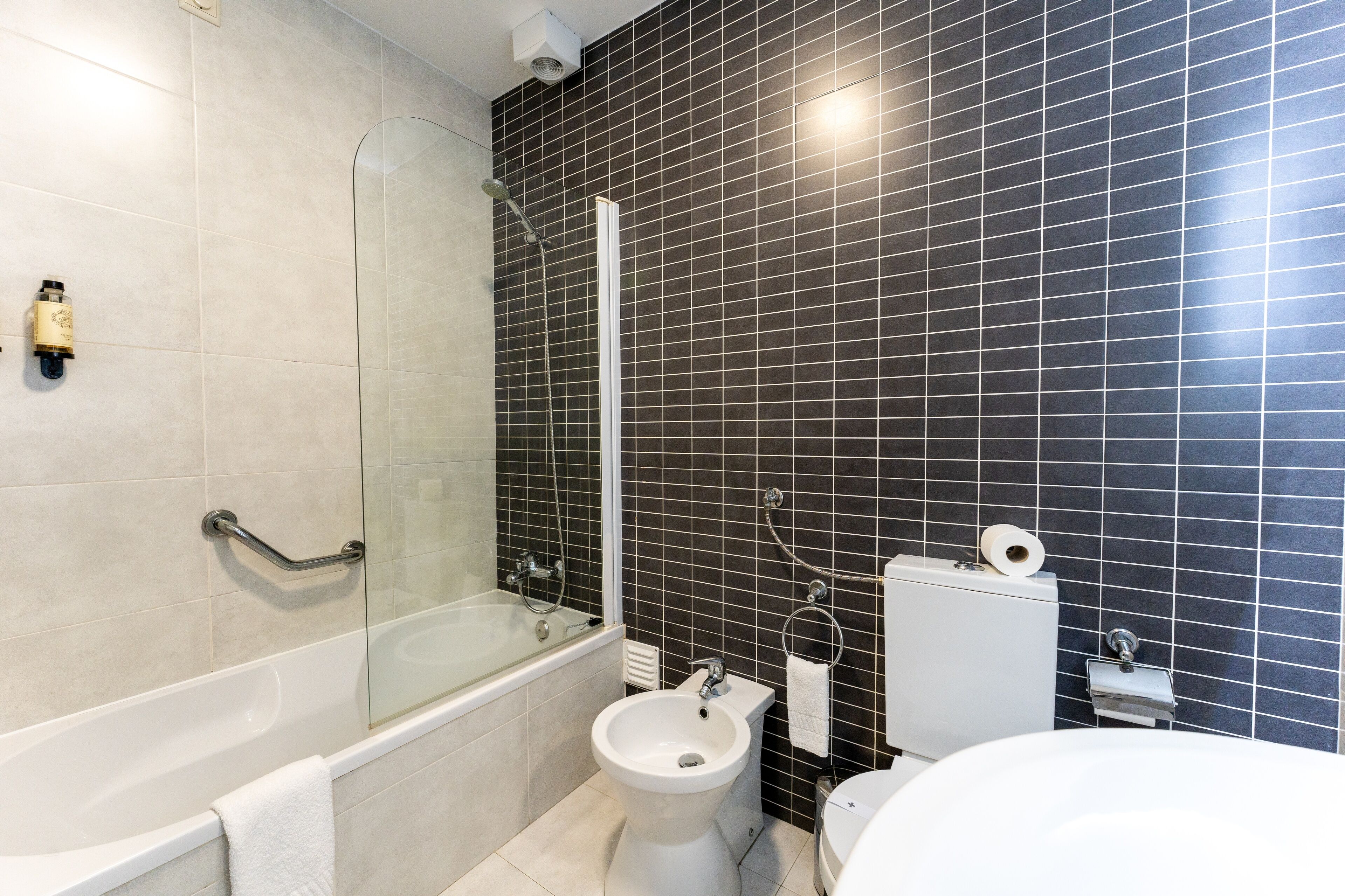 A modern bathroom with a bathtub, bidet, toilet, and a glass-enclosed shower area.