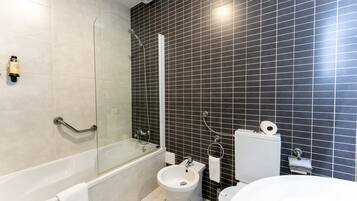 A modern bathroom with a bathtub, bidet, toilet, and a glass-enclosed shower area.