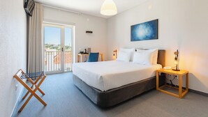 Habitación de hotel con una cama grande, un escritorio, una silla, una lámpara y vistas al exterior.