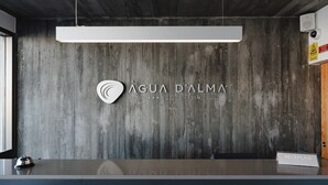 Un mostrador de recepción con un letrero que dice "RECEPCAO" y el logotipo del HOTEL ÁGUA D'ALMA.