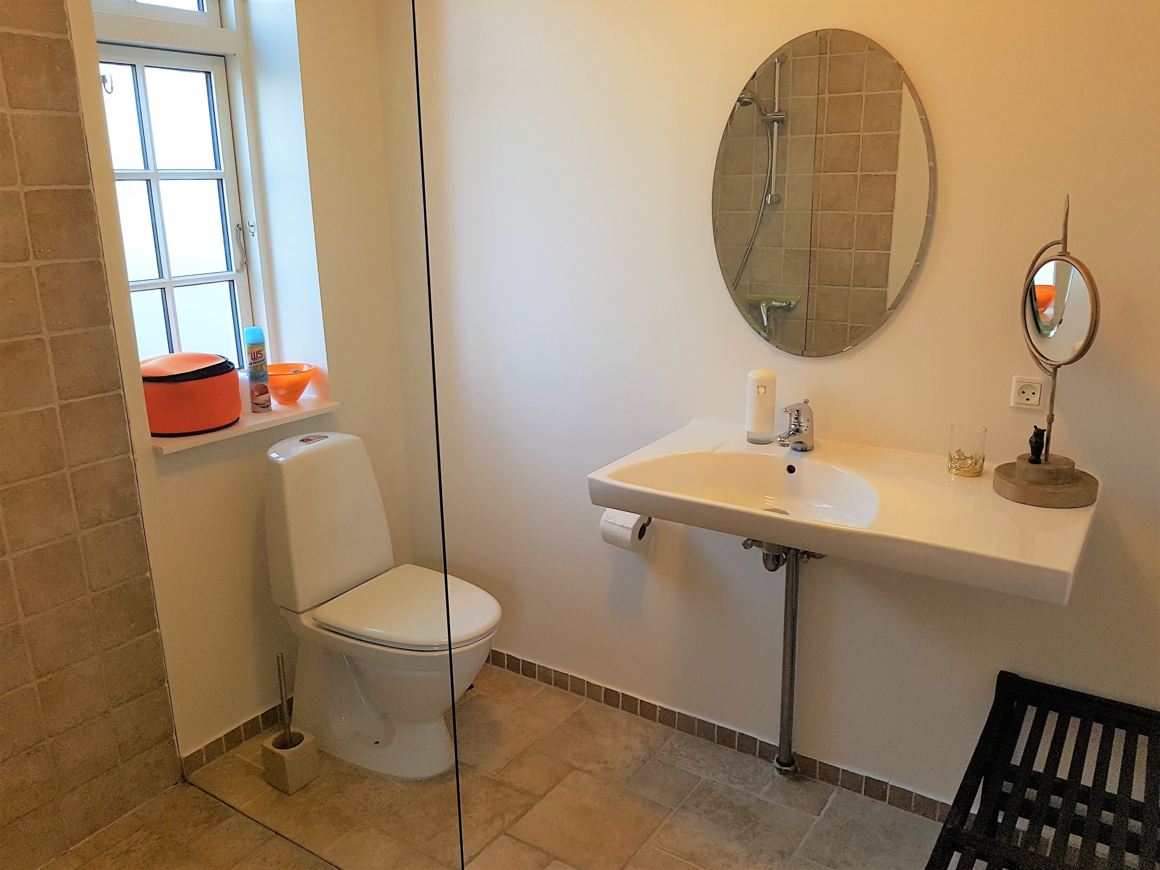 Une salle de bain avec des toilettes, un lavabo et une fenêtre.