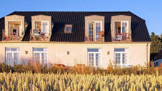 Une maison à deux étages, avec un toit en tuiles, de nombreuses fenêtres et des balcons.