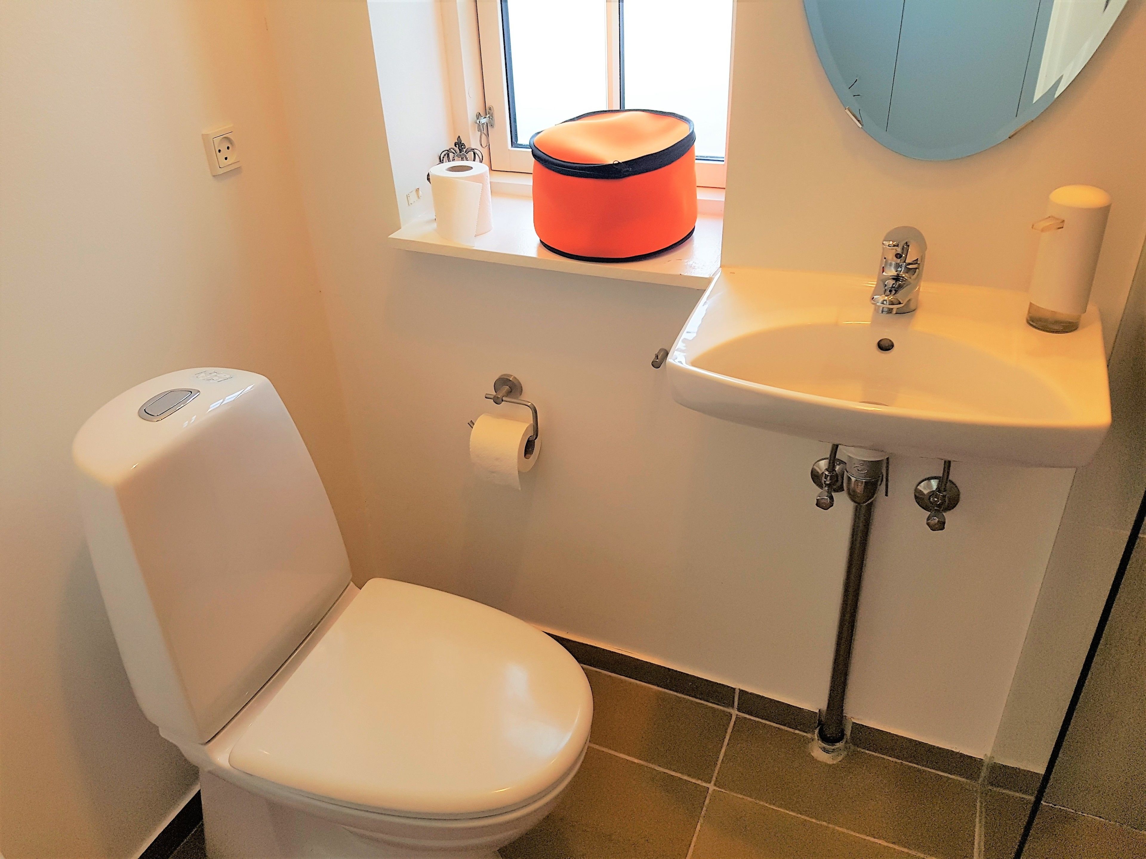 A small bathroom with a toilet, sink, and window.