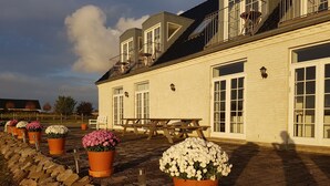 Un bâtiment blanc avec un mur en pierre, une table en bois et des plantes en pot.