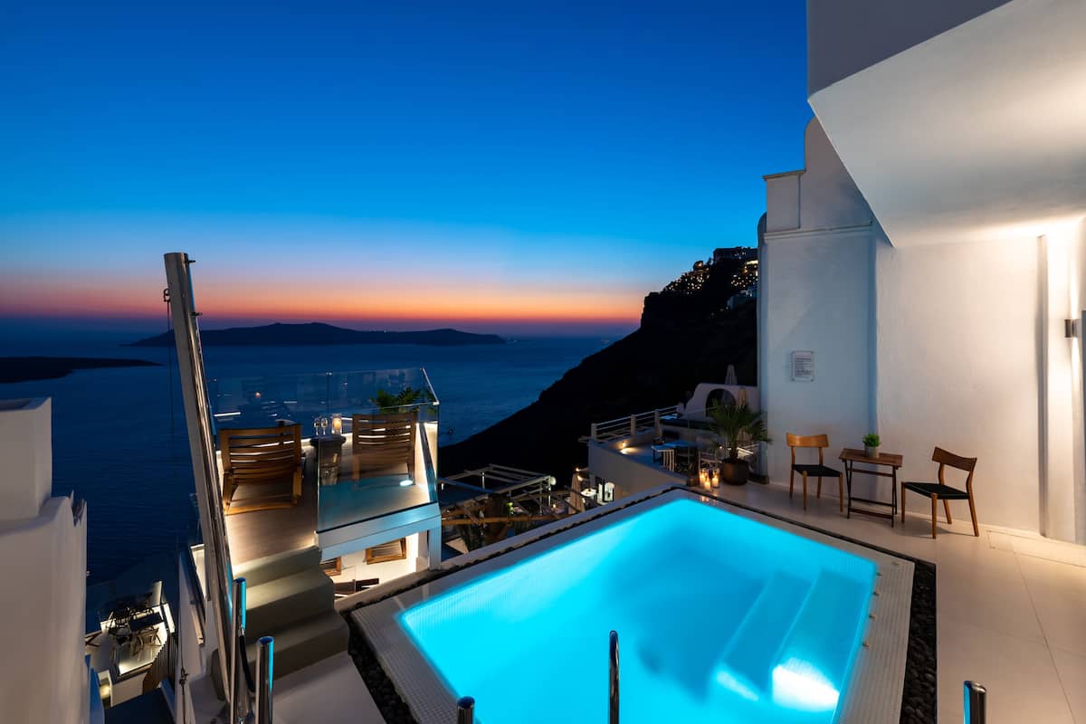 A modern pool area with a view of the sea at dusk.