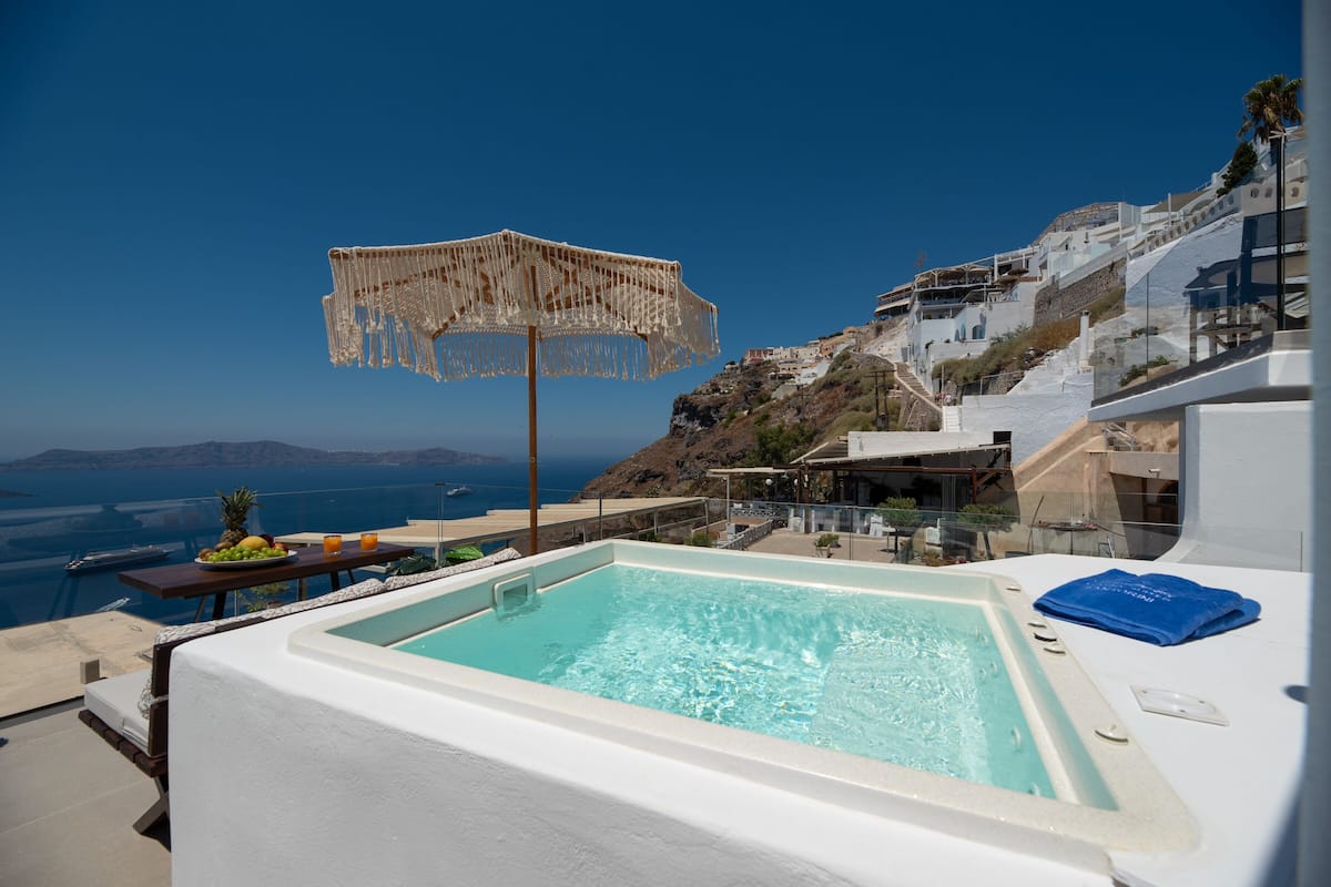 A pool area with a view of the sea and a mountain.
