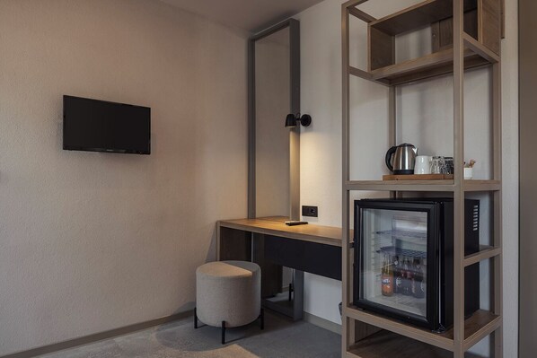 A modern bathroom with a vanity, a toilet, a sink, a mirror, a television, and a refrigerator.