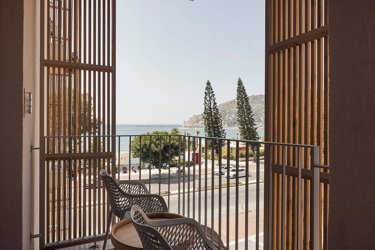 A balcony with a view of the sea and a chair.