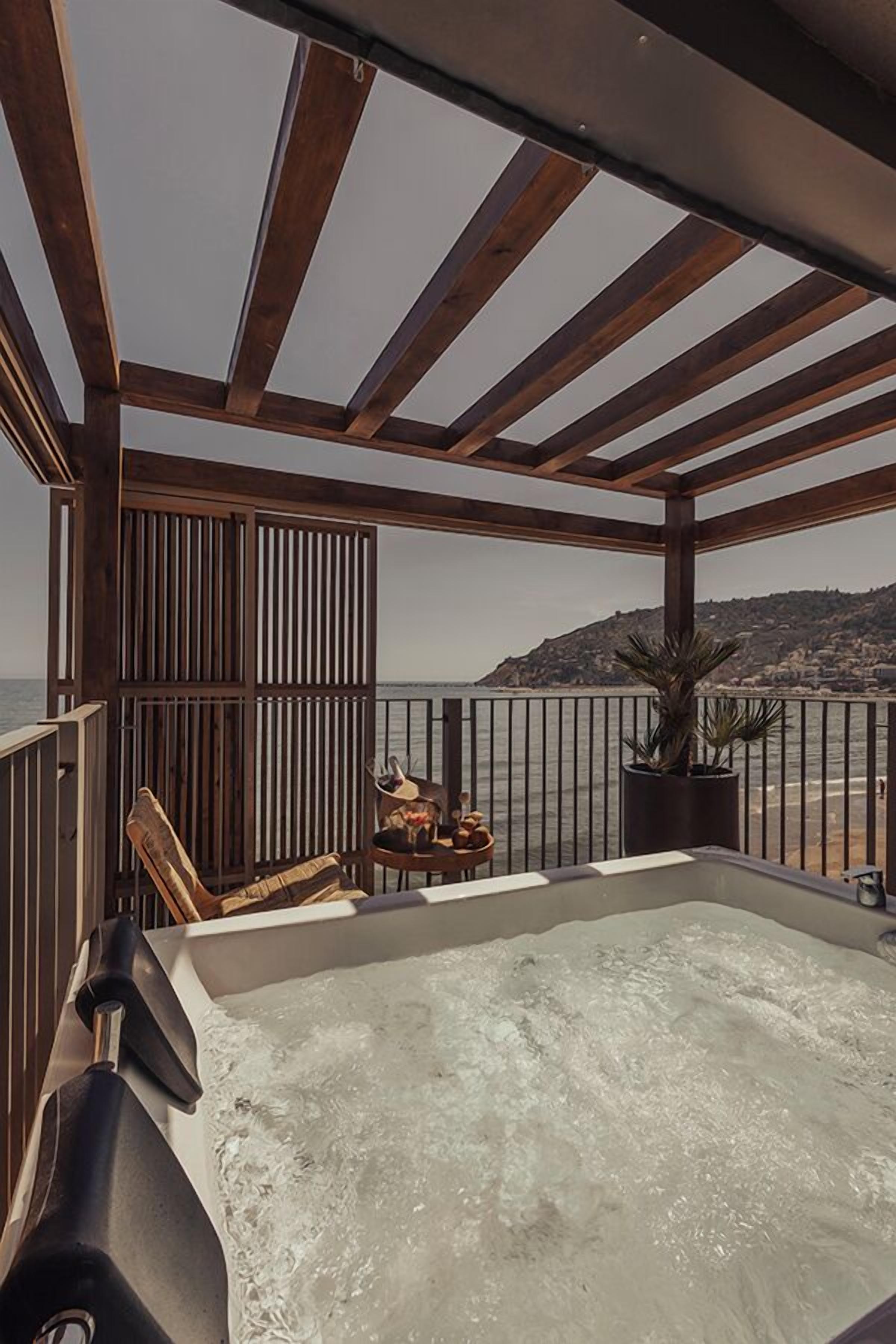 Een jacuzzi met een houten pergola en uitzicht op zee.
