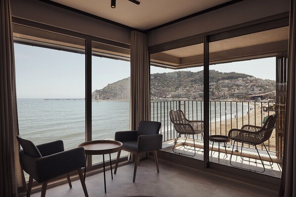 Un balcon avec vue sur la mer et sur le paysage urbain au loin.