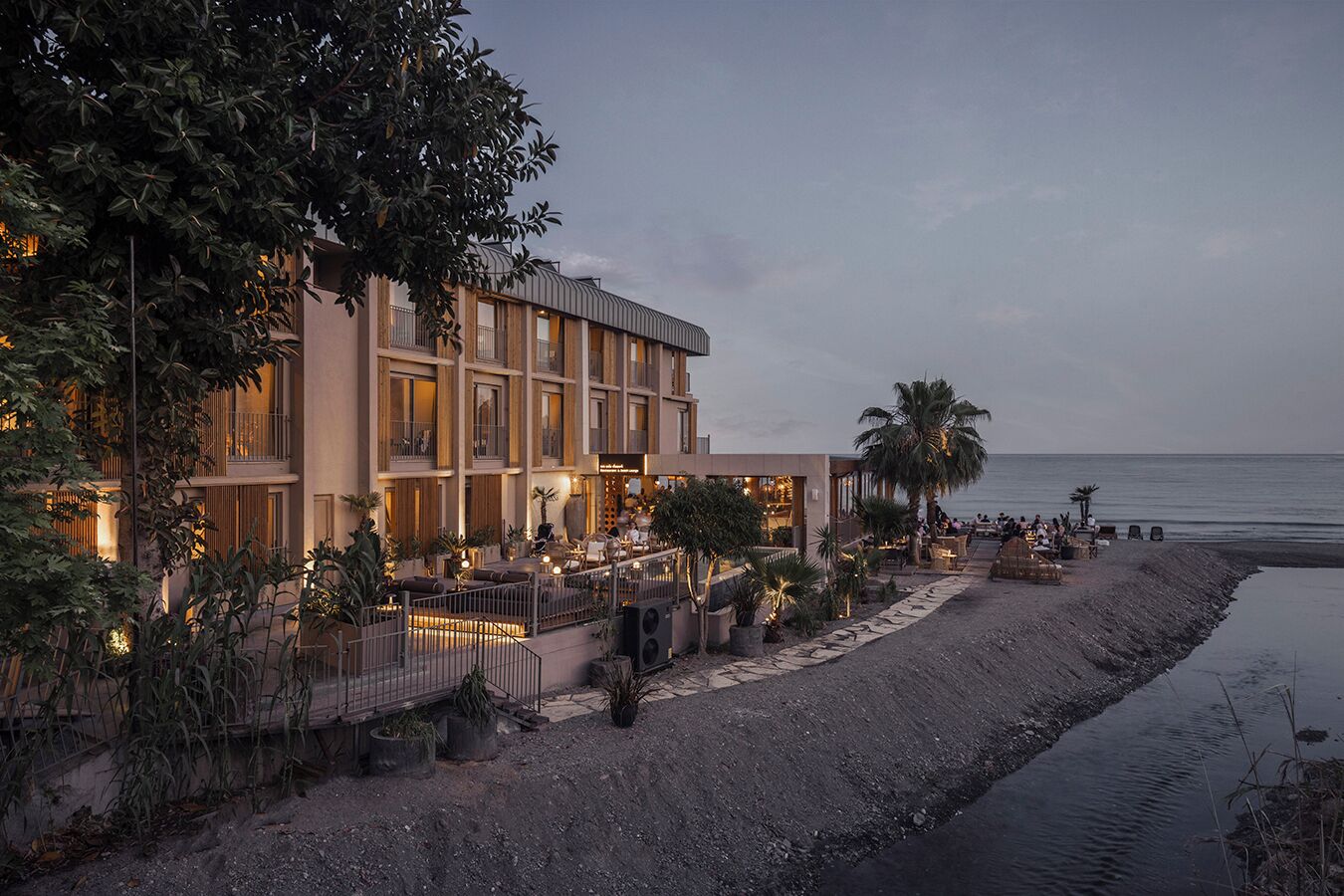 Un hotel con zona de piscina, mobiliario exterior y vista al mar.