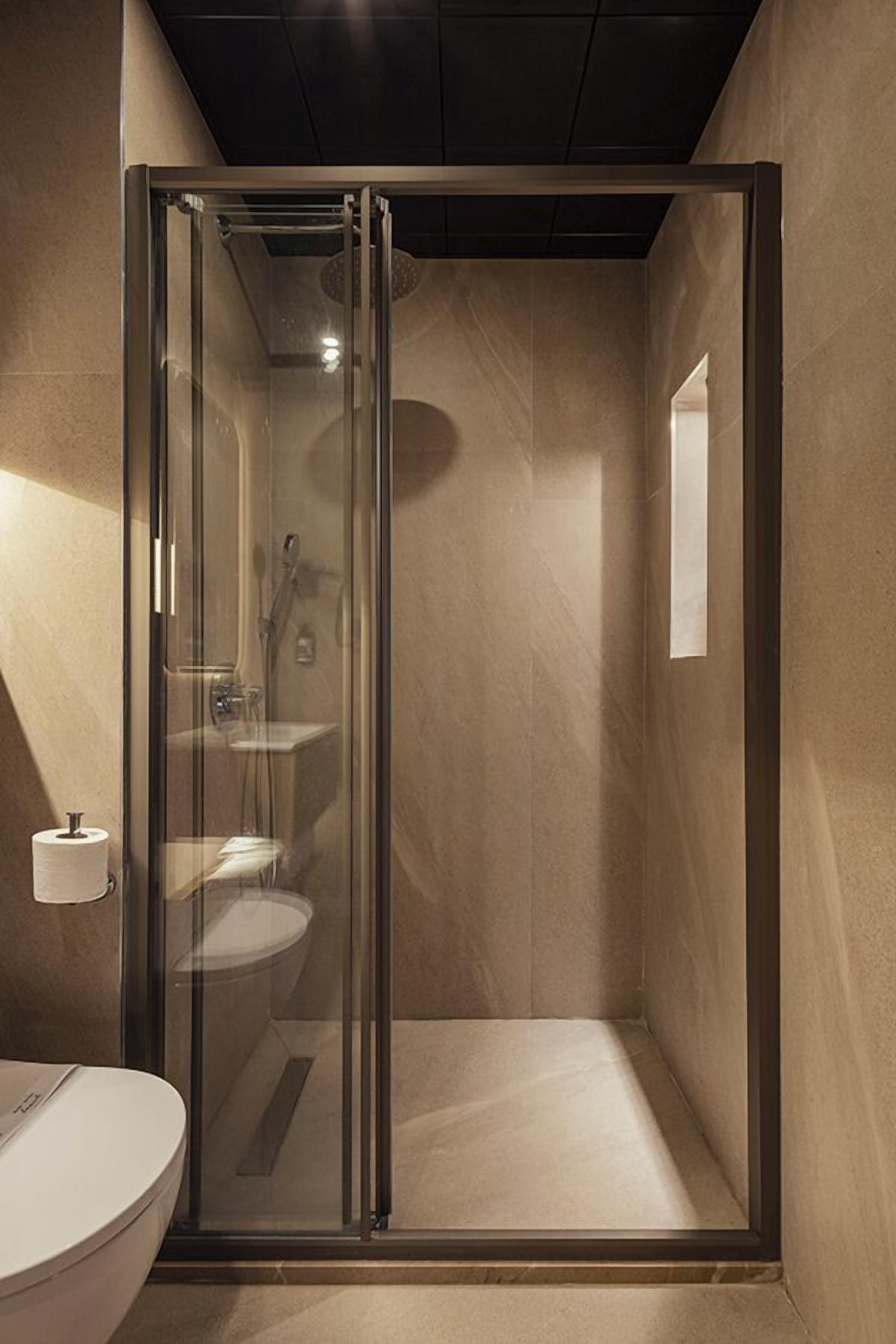 A modern bathroom with a glass-enclosed shower, a toilet, and a sink.