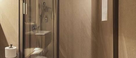 A modern bathroom with a glass-enclosed shower, a toilet, and a sink.