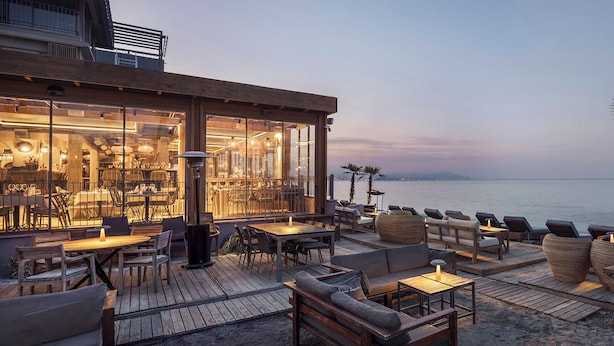 An outdoor seating area with tables and chairs, overlooking a body of water. - En Vie Beach Boutique Hotel - Adult Only (Alanya)