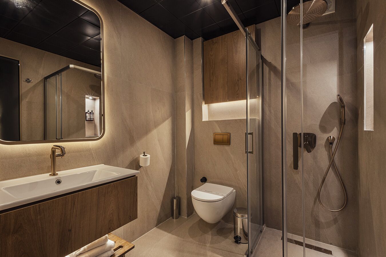 A modern bathroom with a large sink, toilet, and walk-in shower.