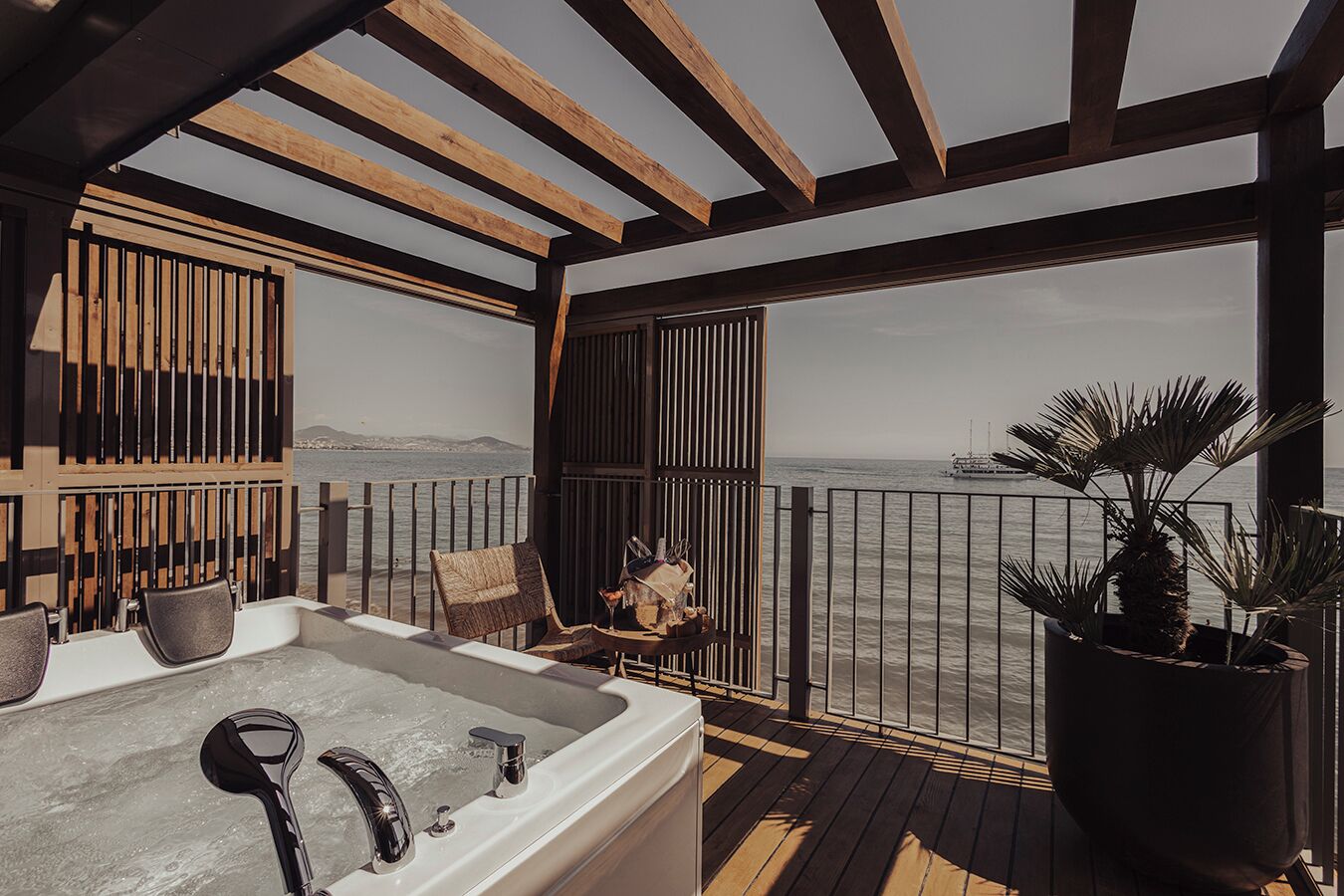 A balcony with a hot tub, seating, and a view of the sea.