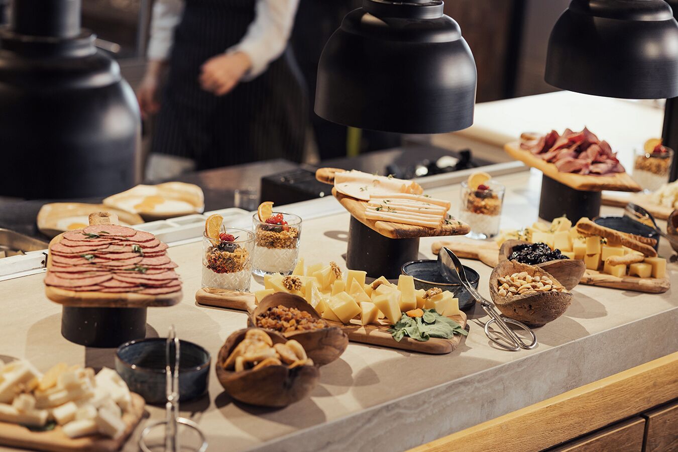 A buffet with various food items including sliced meats, cheeses, and fruits.