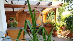 A wooden outdoor seating area with a bench and a potted plant. - Ferienwohnung am Rain (Winden im Elztal)