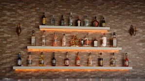 A bar area with multiple shelves of liquor bottles against a brick wall. - Emily Rose Hotel (Kemer)