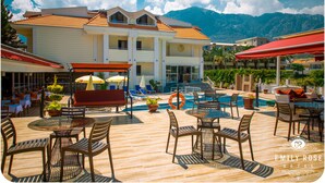 A hotel with a pool area, outdoor seating, and mountain views. - Emily Rose Hotel (Kemer)