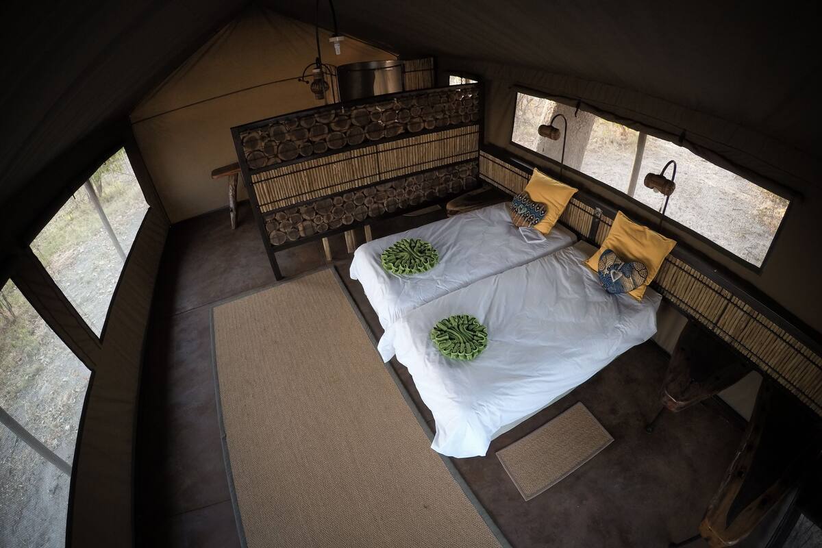Ein Schlafzimmer mit zwei Betten, einem Holzkopfstück und einem großen Fenster.