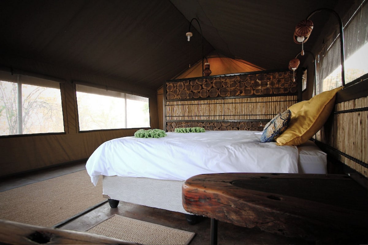 A room with a bed, a wooden bench, and a stone wall.