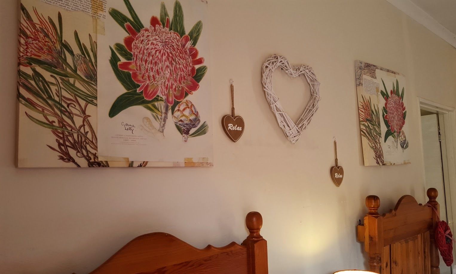 A bedroom with a wooden bed, a wall with botanical artwork, and heart-shaped wall decor.