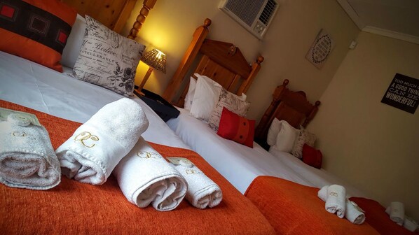 Habitación de hotel con cama, almohadas, mesita de noche y lámpara.
