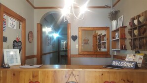Un área de recepción con mostrador de madera, un letrero que dice 'WELCOME' y un espejo que refleja el interior.