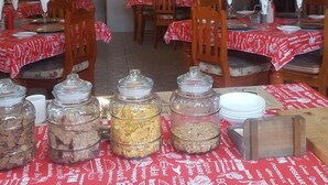 Un comedor con mesas dispuestas para comer, una araña y un panel con la carta.