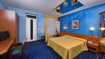 Habitació d'hotel amb llit, escriptori, cadira, televisió i mirall de bany.