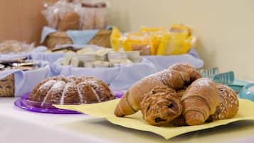 Une table de buffet proposant une variété de viennoiseries et de desserts, notamment des croissants et des petits pains.