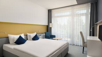 Habitación de hotel con cama, escritorio, silla y vistas al exterior.
