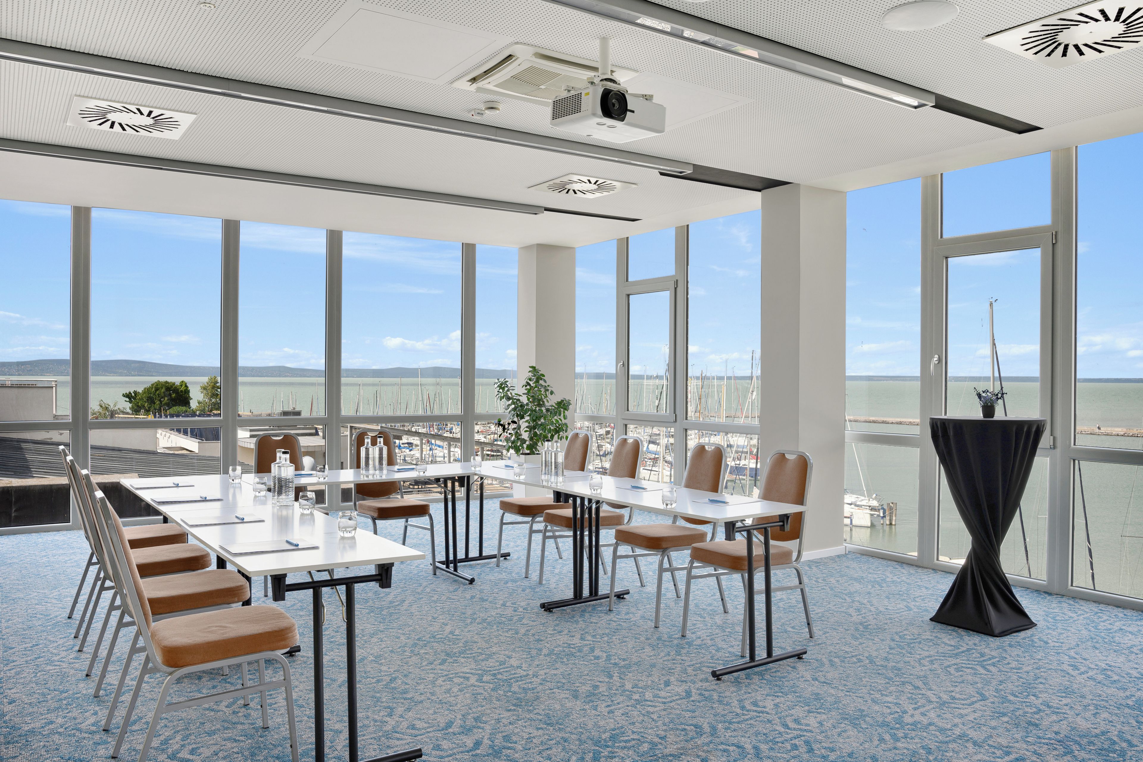 A conference room with a large table, chairs, and a view of the marina through large windows.