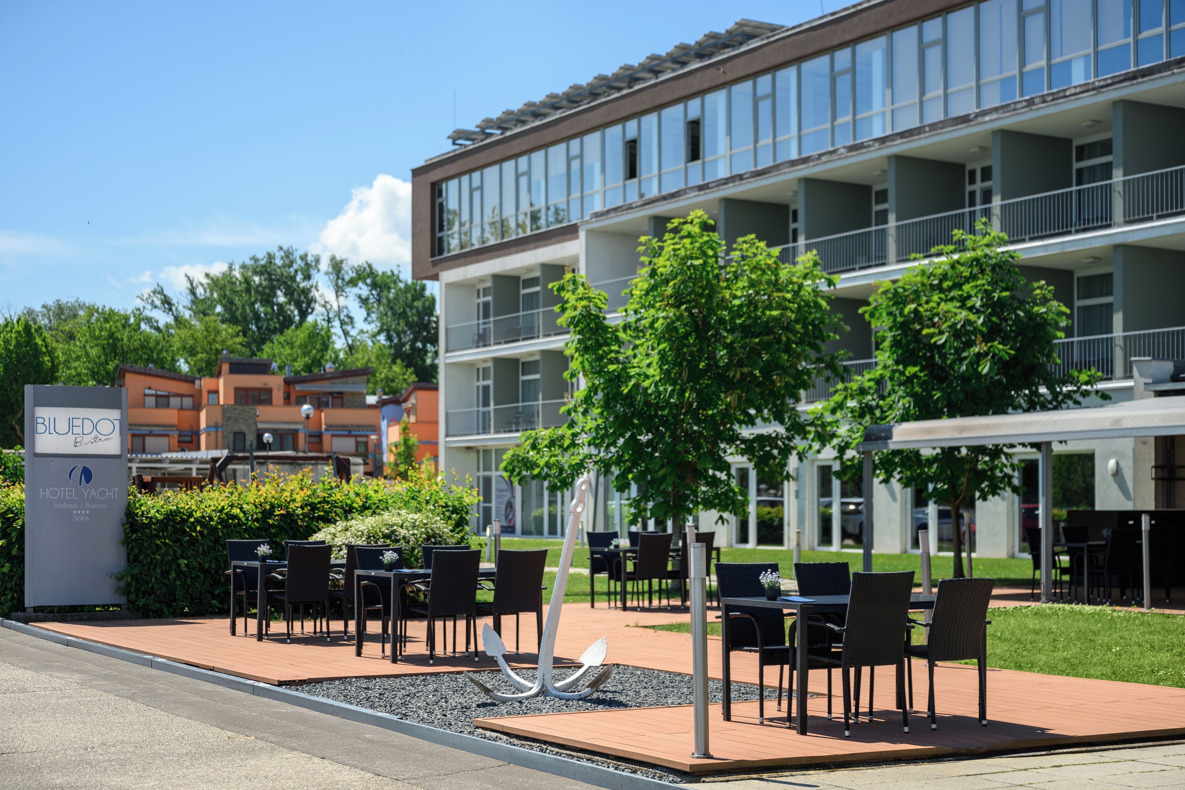A hotel exterior with outdoor seating, a signboard, and a building with multiple floors.