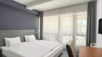 Una habitación de hotel con una cama grande, un escritorio, una silla y un televisor.