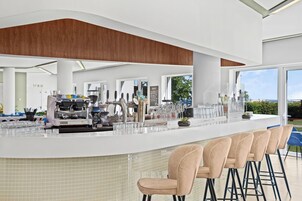 Un área de bar moderna con mostrador, taburetes y una máquina de café.